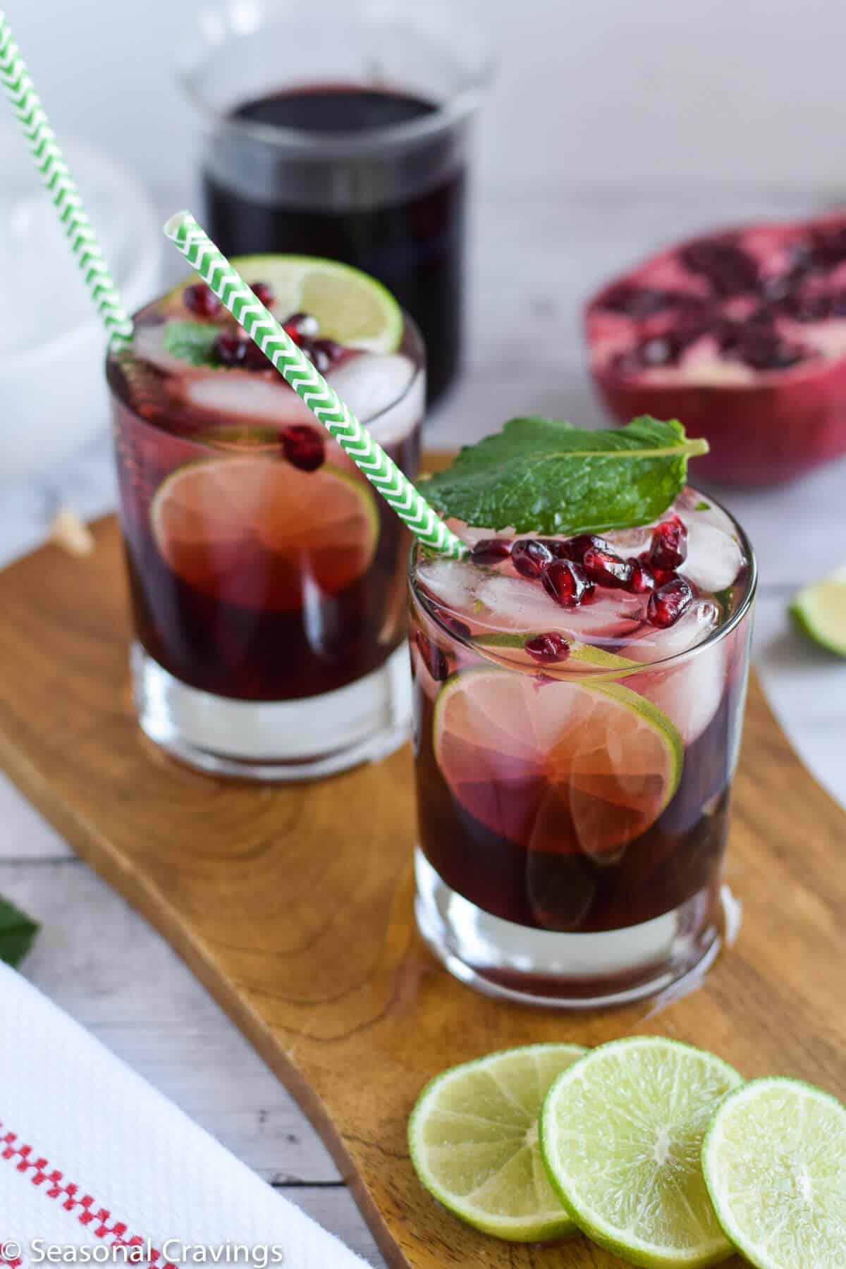 Easy Pomegranate Mojito in two glasses with green straws and mint