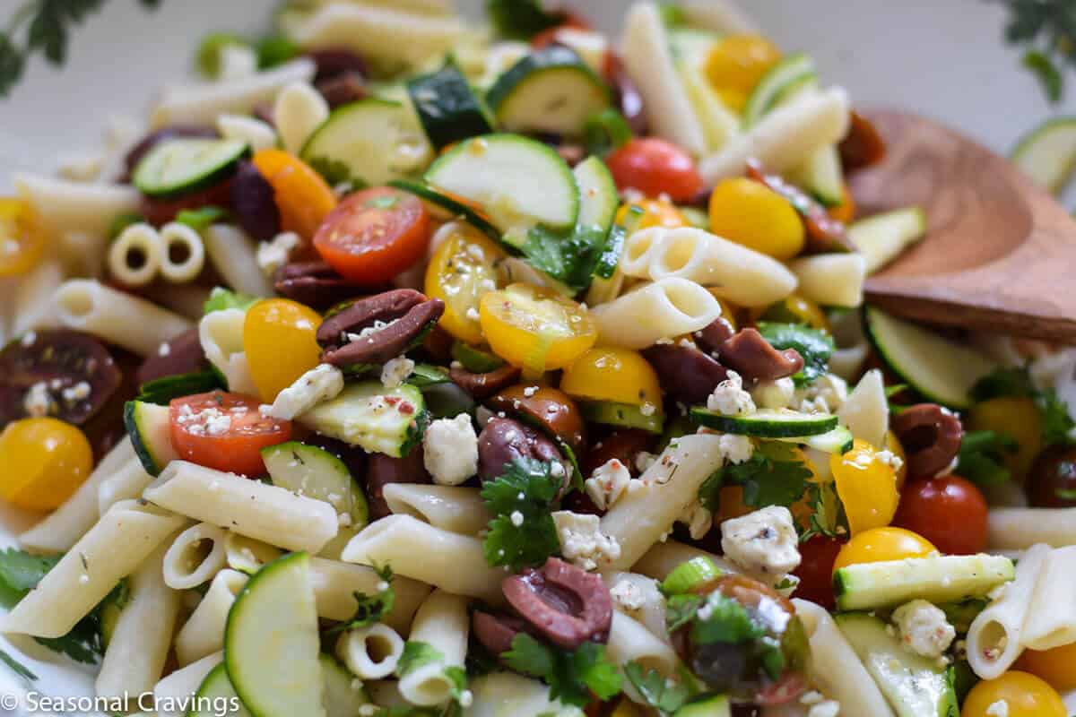 Greek Pasta Salad with tomatoes, olives, parsley and feta close up