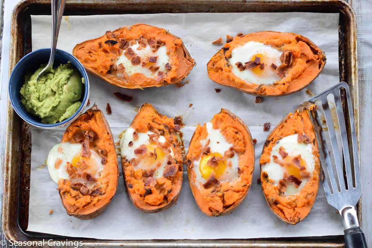 Baked Sweet Potatoes with Egg topped with bacon and guacamole on the side