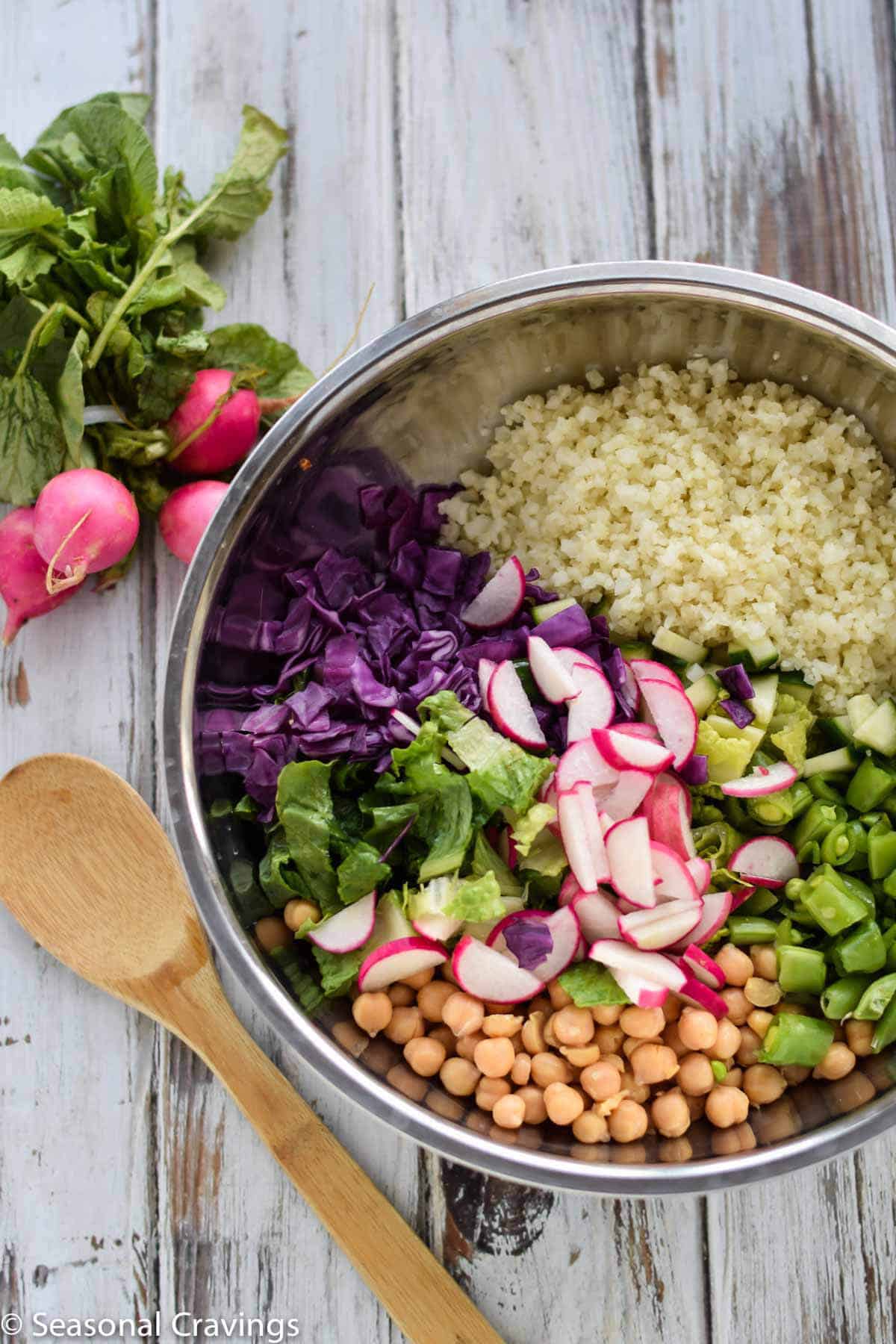 Green Cauliflower Rice Salad in silver bowl with wooden spoon