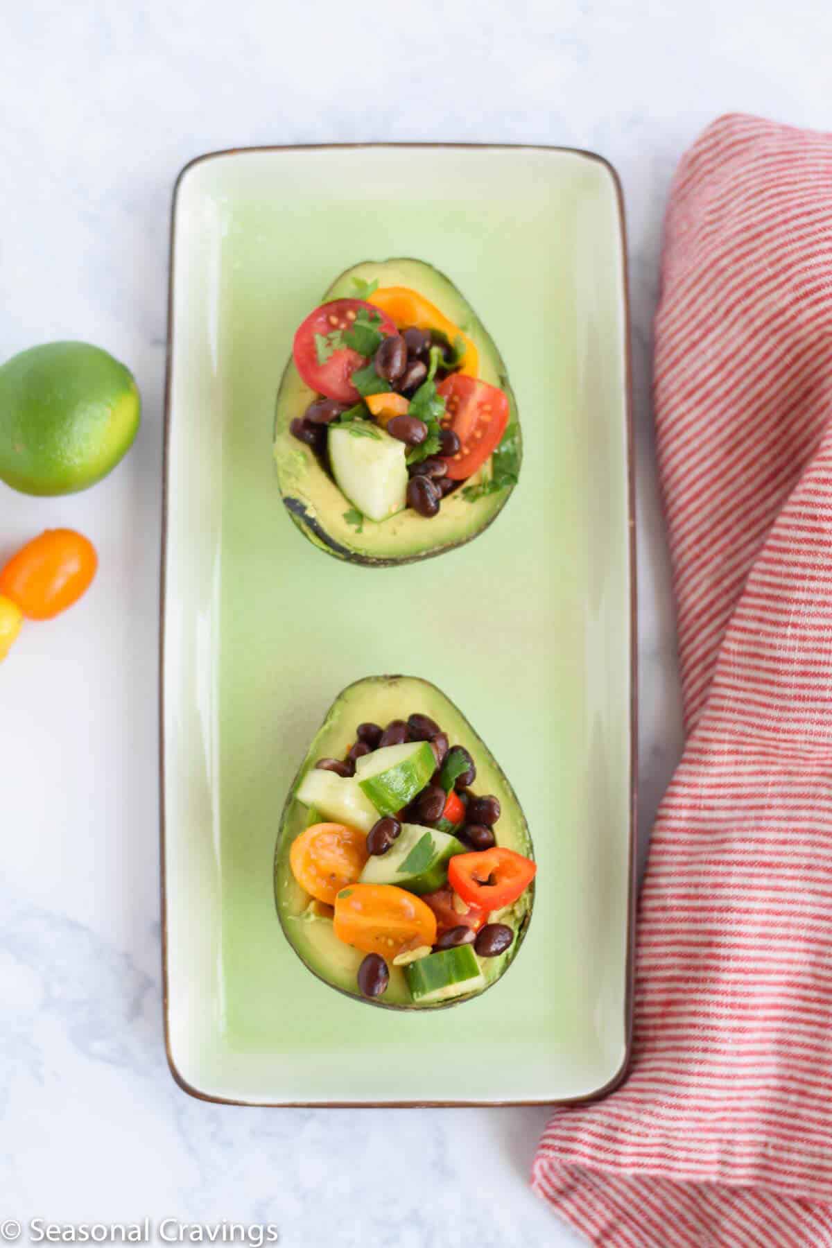 Skinny Cucumber and Tomato Salad in two avocados on a green plate