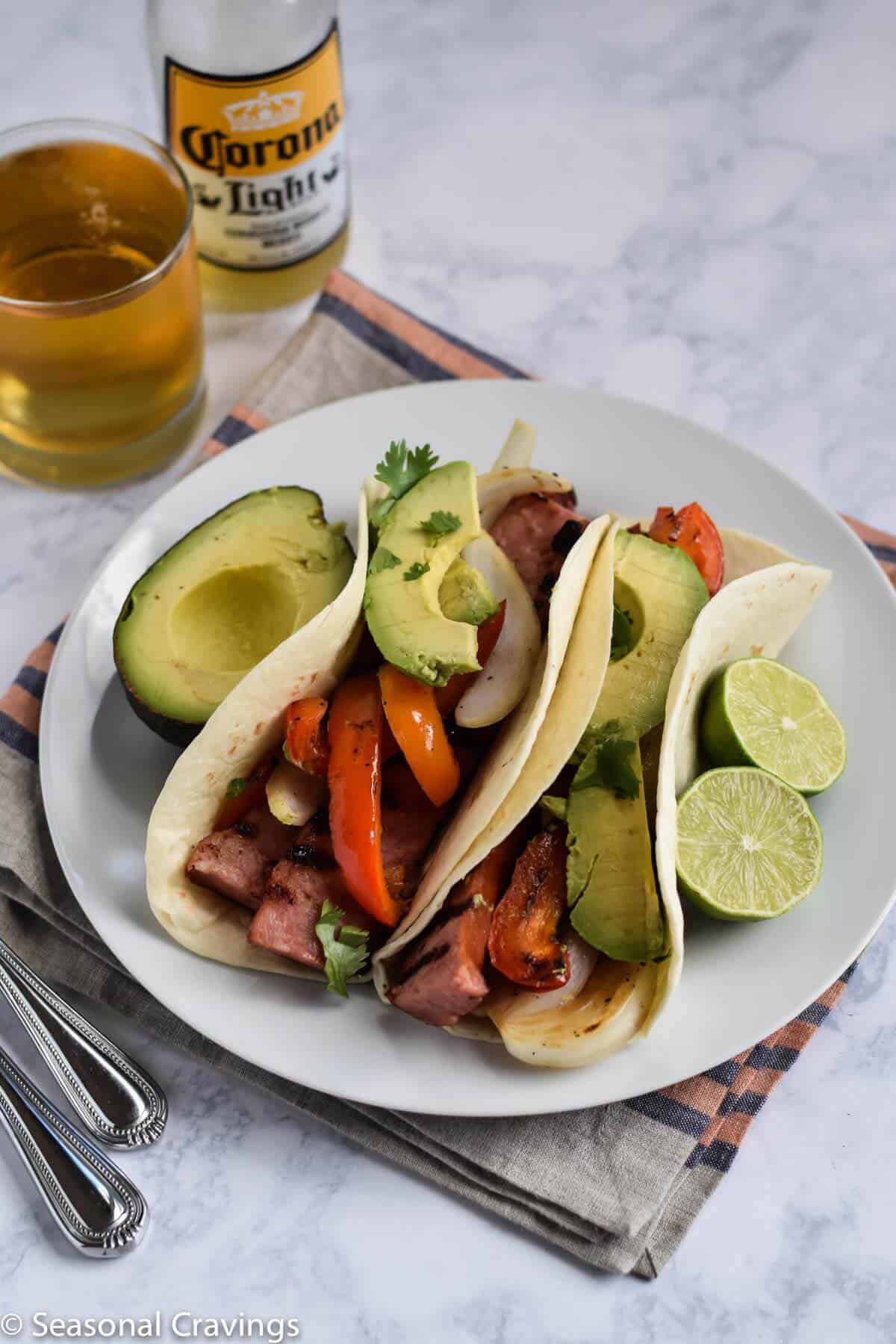 Grilled Sausage Tacos on a white plate with avocado slices