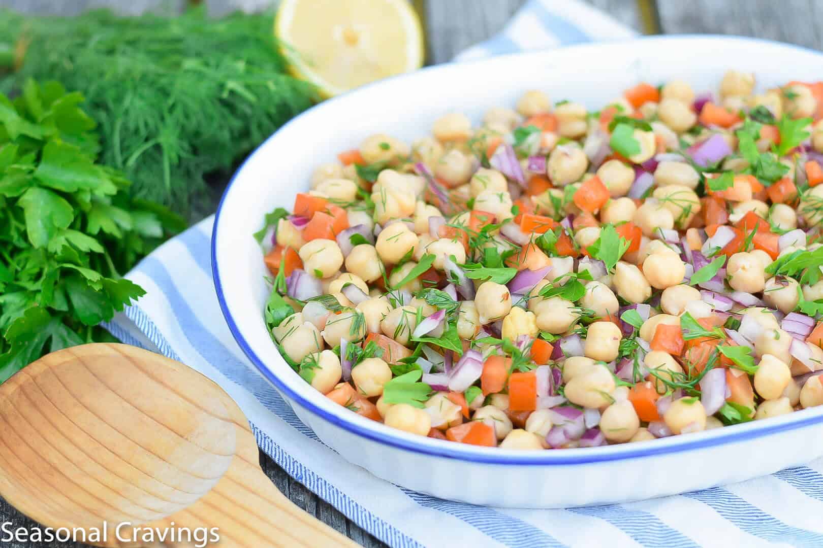 Summer Chickpea Salad with a wooden spoon in a white bowl