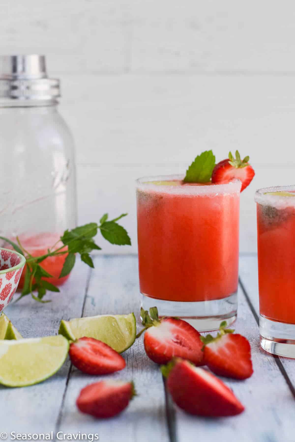 lime rickey gin drink in a glass with strawberries and limes