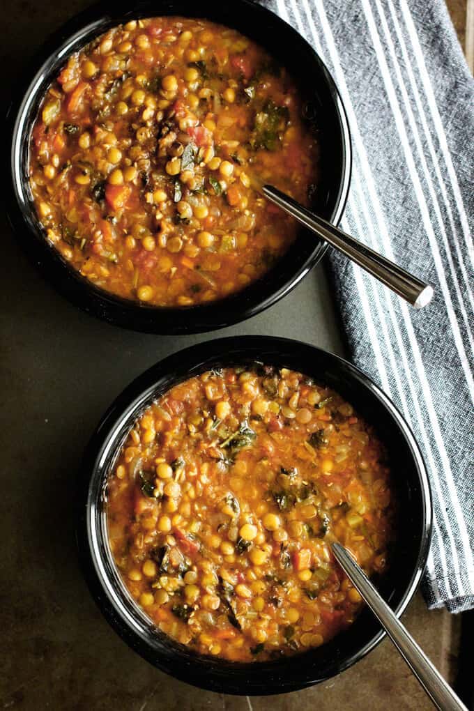 Lentil and Kale Soup in two black bowls with spoons