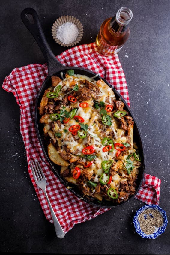 Pulled Pork Loaded Fries topped with cheese and jalepenos in a cast iron skillet