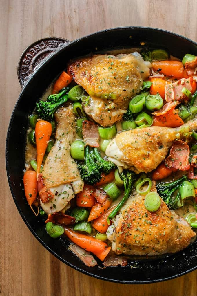 White Wine Braised Chicken with carrots, broccoli and onions in a cast iron skillet