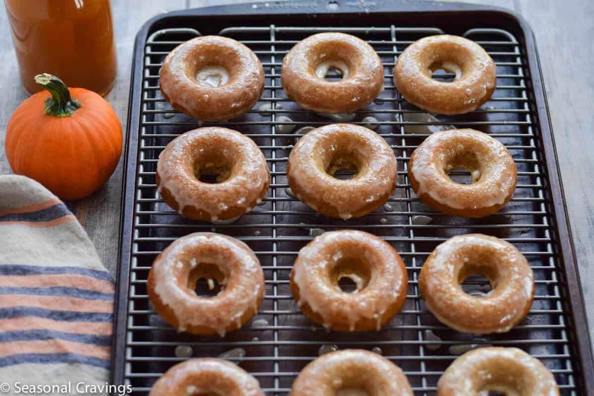 Gluten Free Apple Cider Doughnuts on a cooling rack with glaze