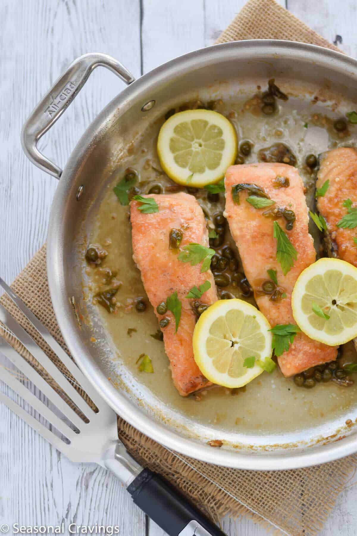 Gluten Free Salmon Piccata with lemon and parsley in a pan with spatula