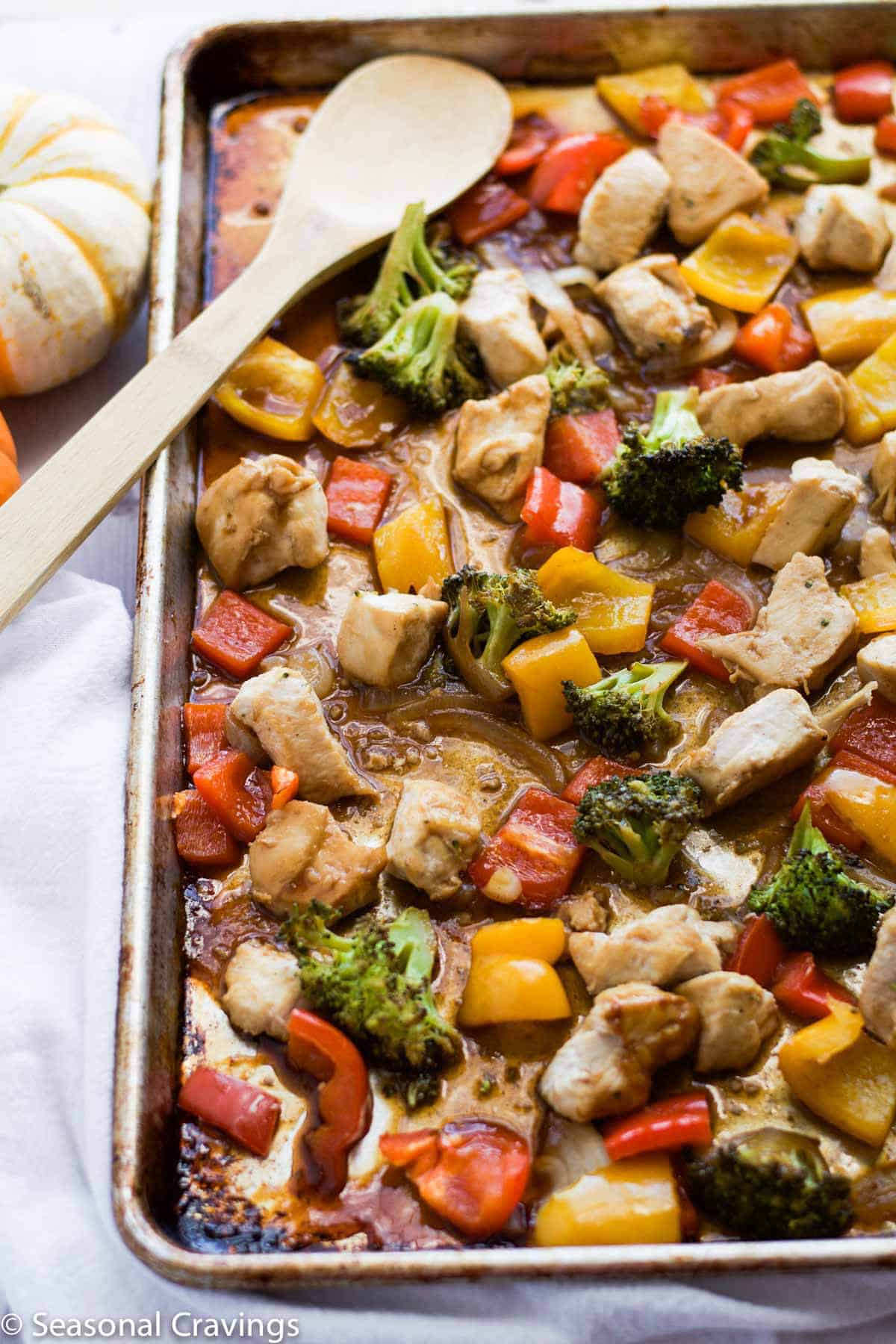 stir fry chicken with vegetables in a sheet pan with a wooden spoon