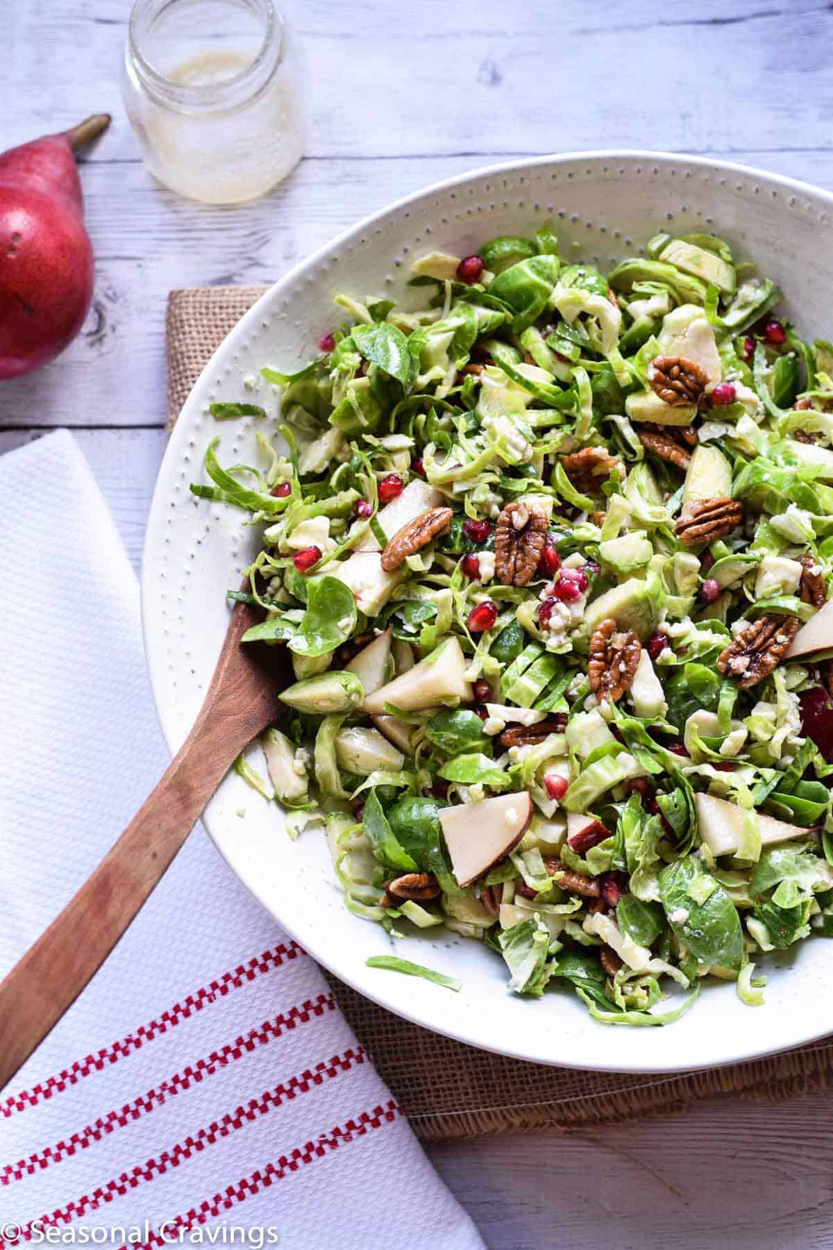 Brussel Sprout Salad with Pear and Pomegranate in a white bowl