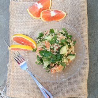 A plate of grapefruit and quinoa salad with a fork.