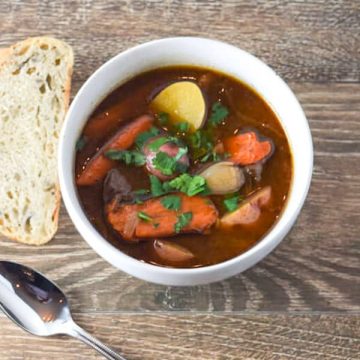 Not your average beef stew with carrots and bread on a wooden table.