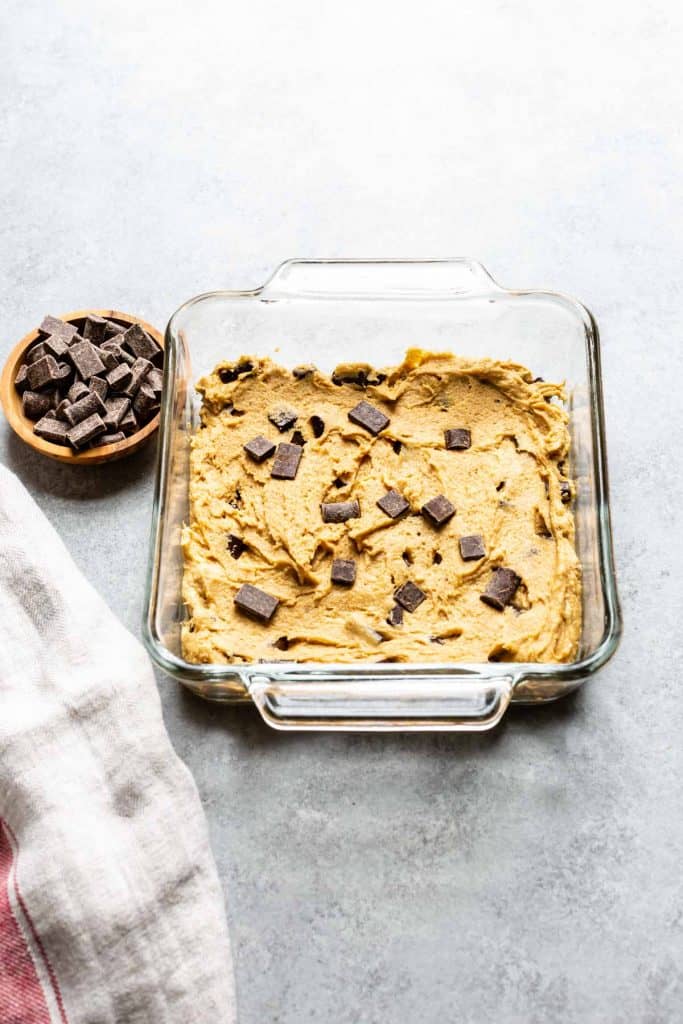 chocolate chip cookie batter in a glass pan