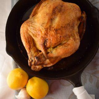An easy roast chicken in a cast iron skillet with lemons.