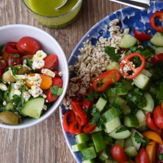 A plate of salad with cucumbers, tomatoes and olives.