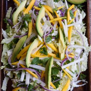 A plate of cabbage salad with avocado and onions.