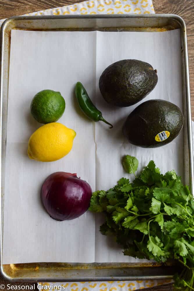  Guacamole ingredients on a sheet pan with limes lemons and avocados