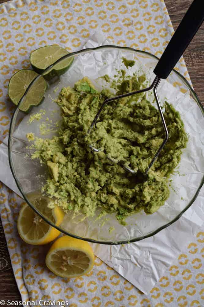 Guacamole in a bowl with a potato masher