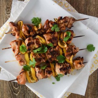 Pineapple grilled chicken skewers on a white plate.