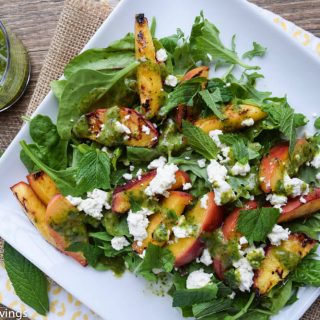 A plate of peach salad with feta and greens.