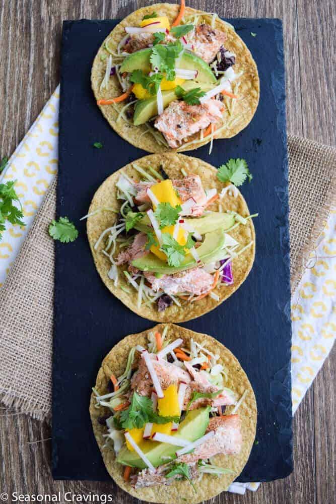 Salmon Tostadas with mango and avocado on a black tray