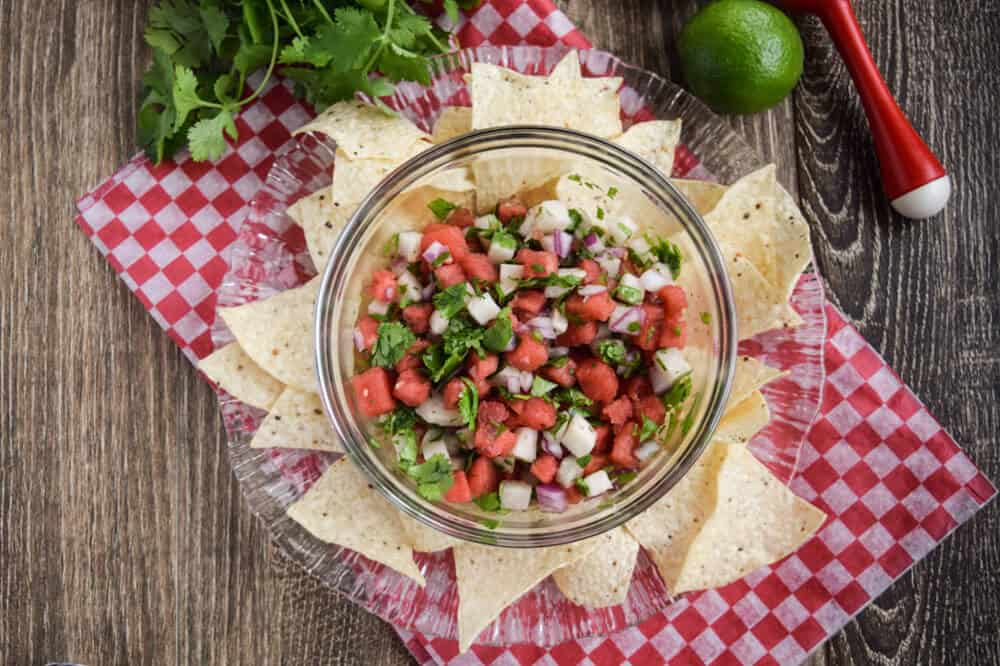 Watermelon salsa with jicama with chips on a red and white cloth