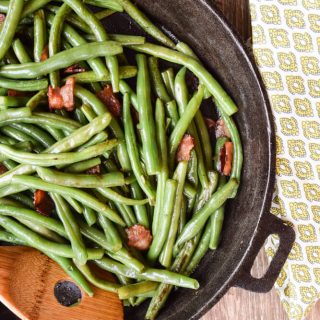Green beans sautéed in a cast iron skillet with bacon.