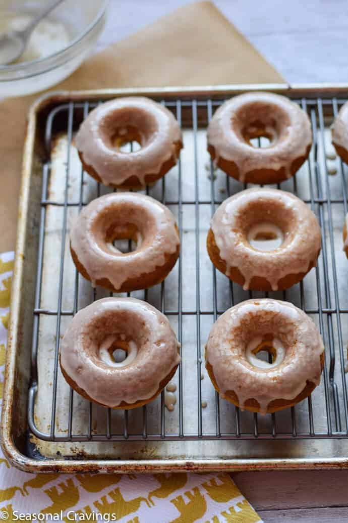 Easy Gluten Free Pumpkin Doughnuts light, flaky and topped with maple icing on a sheet pan.
