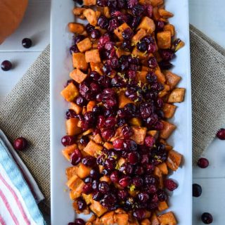 Roasted maple sweet potatoes and cranberries salad on a white plate.