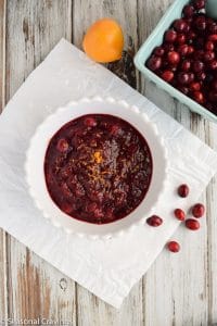 Cranberry pomegranate sauce on a white table with cranberries.