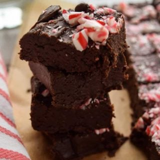 A stack of chocolate brownies with peppermint candies on top, transformed into the easiest two ingredient fudge.