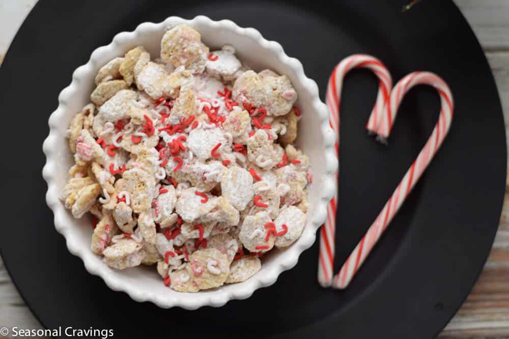 Christmas Puppy Chow on a black plate in a white bowl