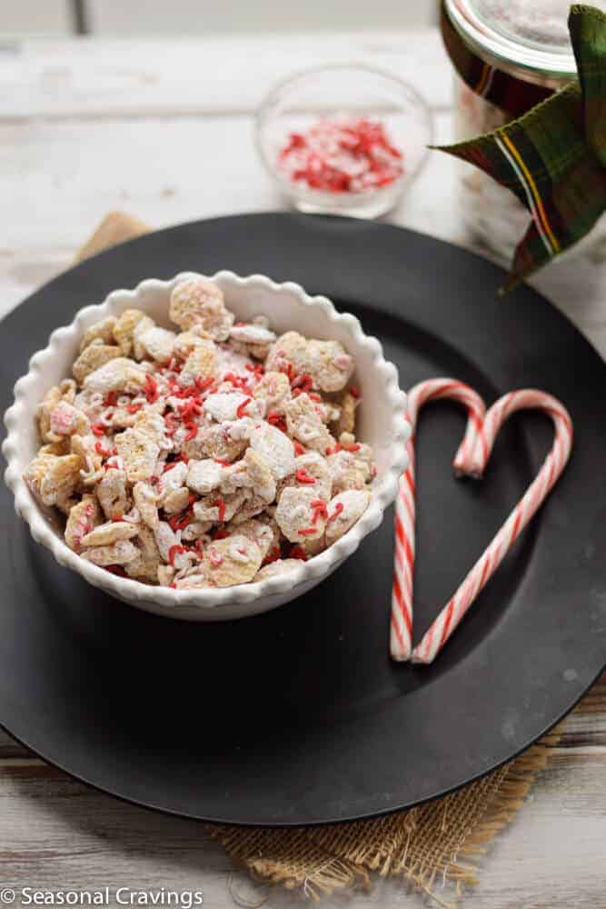 Peppermint Puppy Chow on a black plate with two candy canes on side