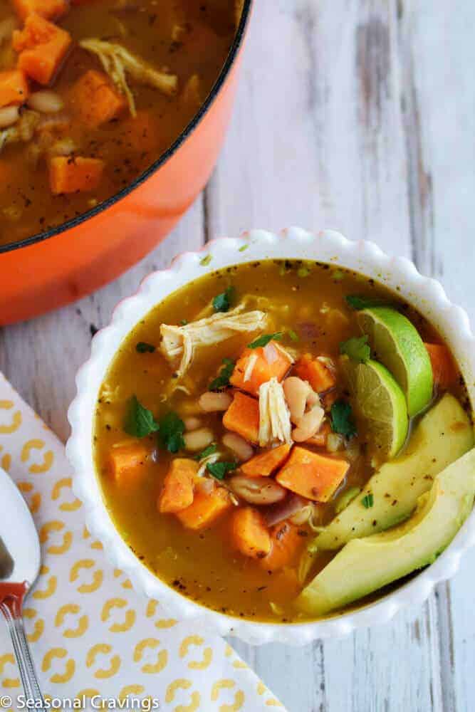 White Chicken Chili with Sweet Potatoes in a white bowl with a spoon