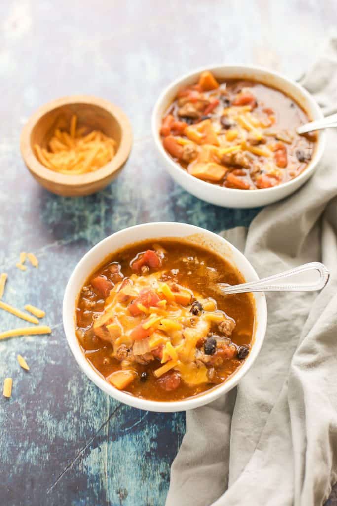 turkey chili in white bowls with cheese on top