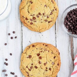 A gluten-free single-serve chocolate chip cookie resting on a wooden table.