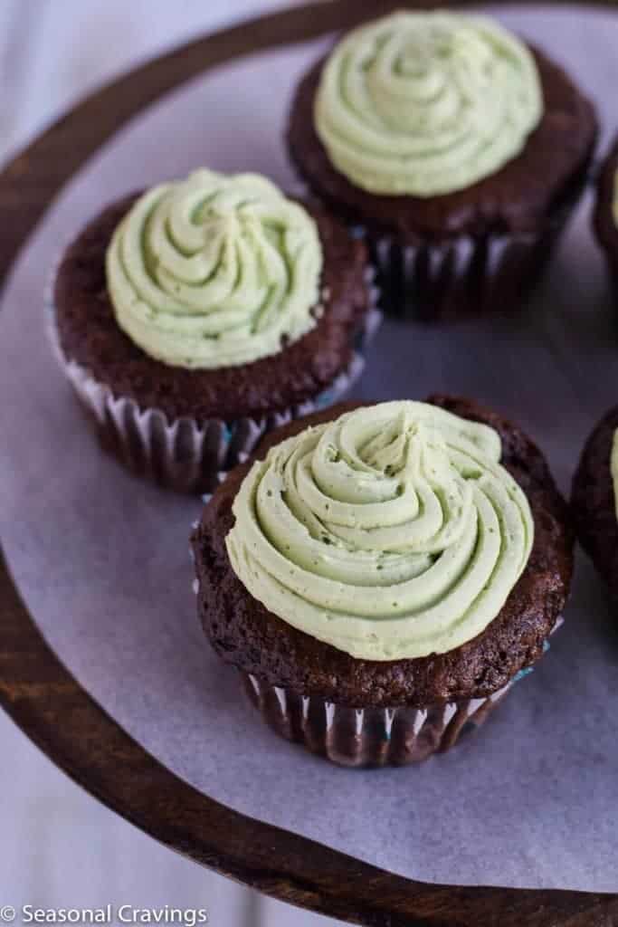 Four gluten-free St. Patrick's Day cupcakes with green frosting on a plate.