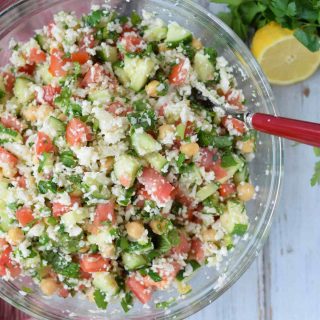 A bowl of cauliflower tabbouleh salad with tomatoes and cucumbers.