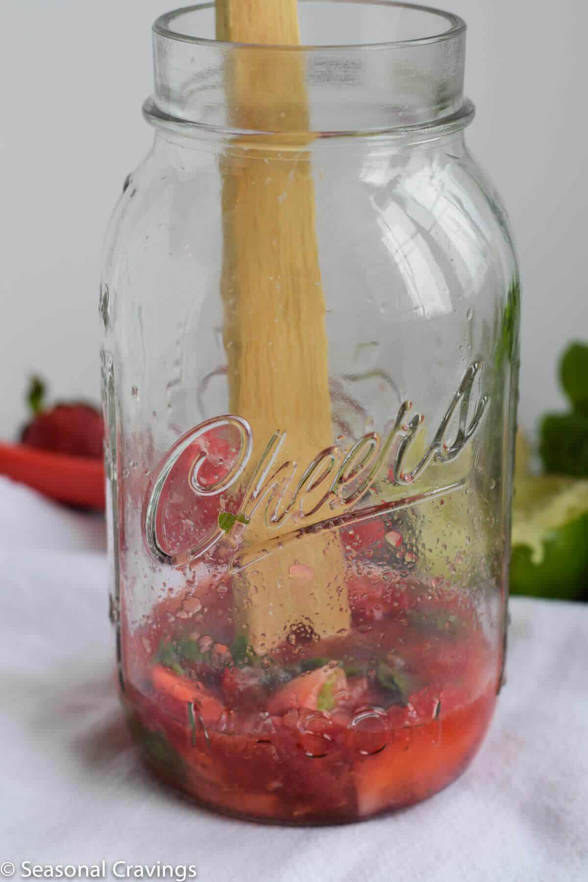 Muddling Strawberry Mint Smash with a wooden spoon.