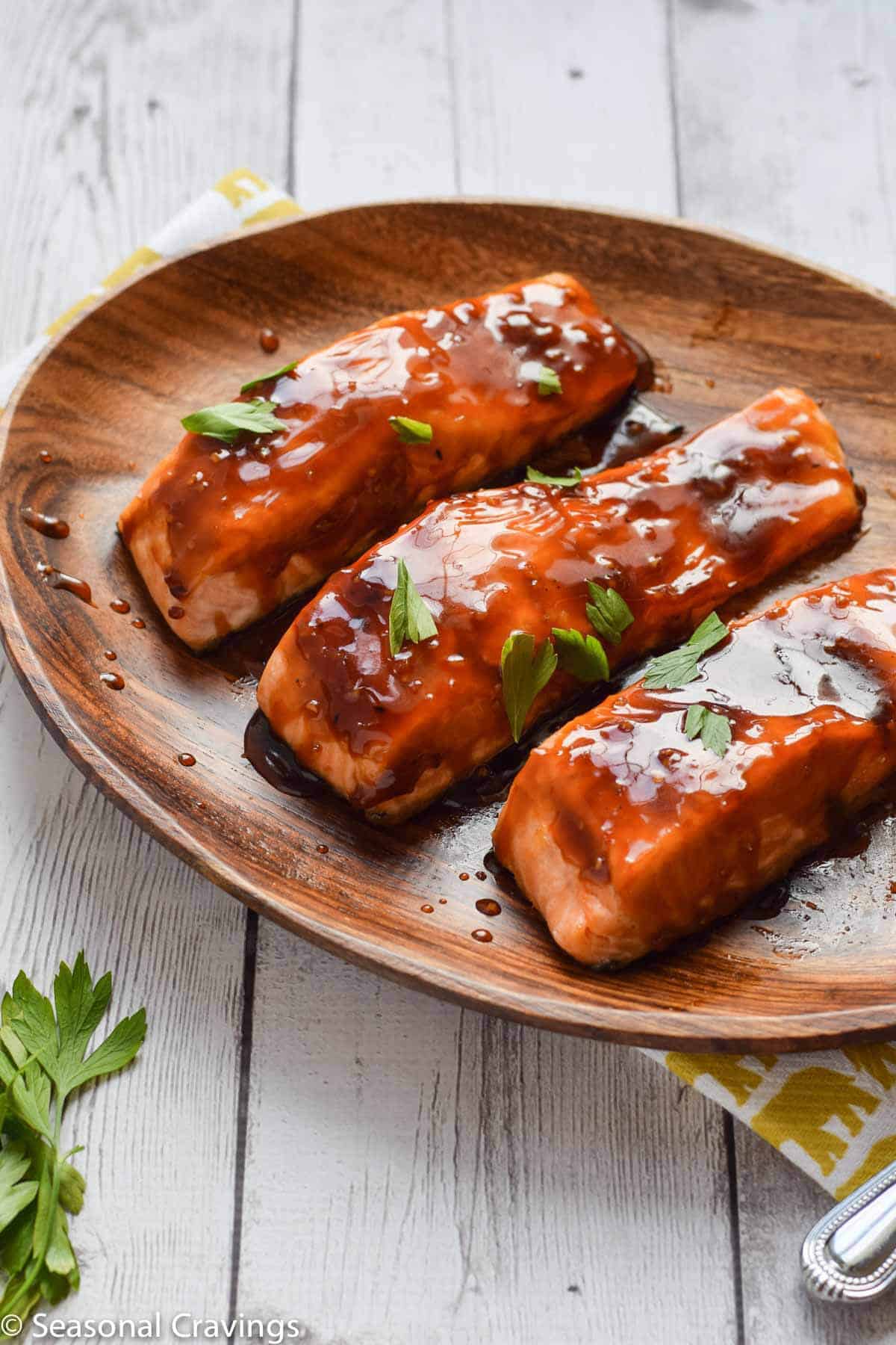 Salmon teriyaki with sweet sticky glaze on a wooden plate.