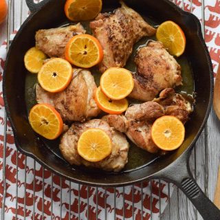 A flavorful cast iron skillet filled with five spice chicken and orange slices.