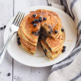 Paleo blueberry pancakes on a white plate with a fork.