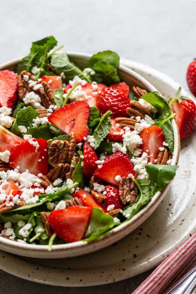 close up of kale salad with strawberries, feta and pecans