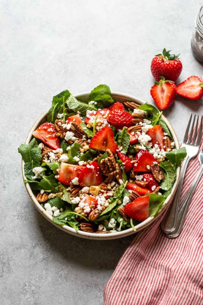 strawberry and pecan salad with feta cheese in a white bowl