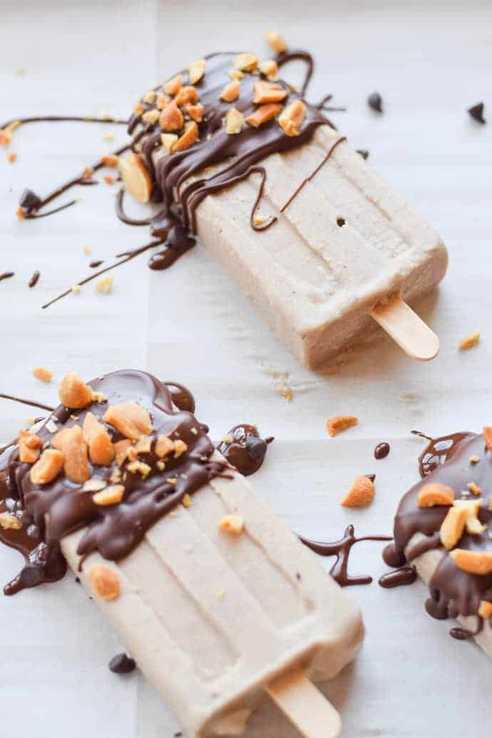 Schokoladen-Erdnussbutter-Bananen-Eis am Stiel auf weißem Pergamentpapier