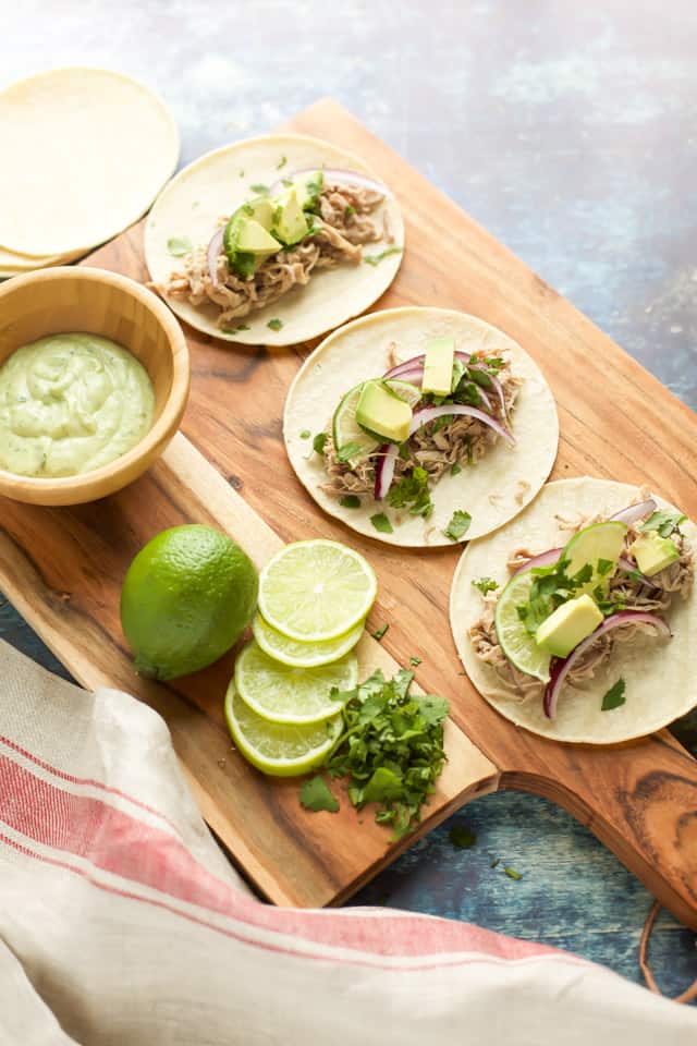 Pork Carnitas Instant Pot with avocado and limes on a wooden board