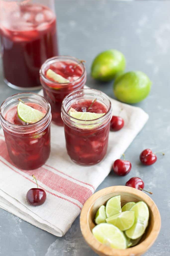 Cherry Margaritas in three glasses with limes