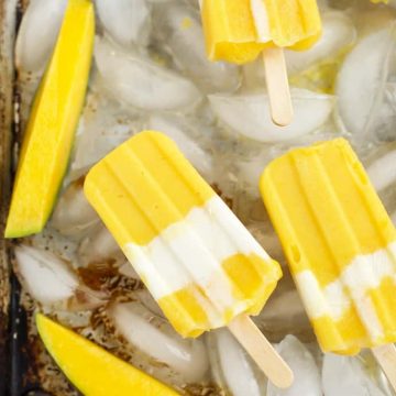 Mango yogurt popsicles on ice in a pan.