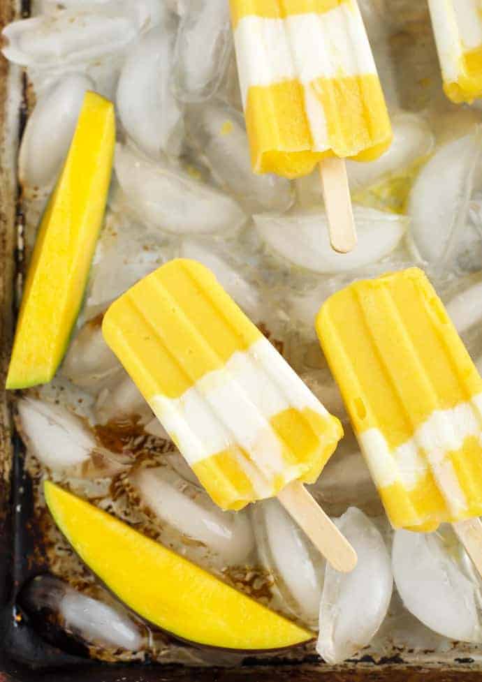 Mango popsicles on a sheet pan with ice